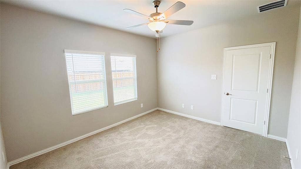 505 Blanton Street, McKinney, TX 75069 Neutral tone wall paint, carpet flooring, two windows with blinds, ceiling fan with integrated lighting, and a white interior door