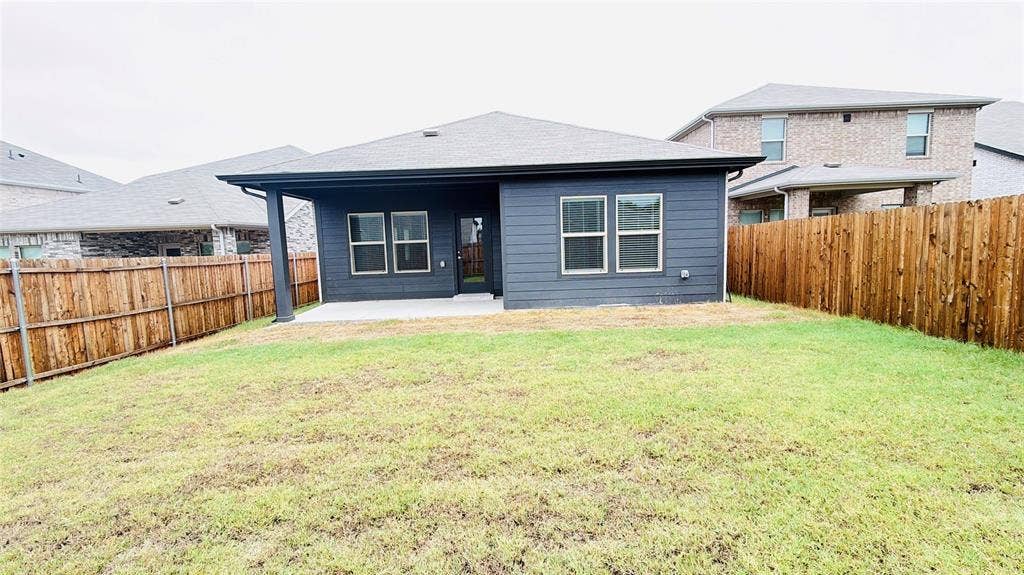 505 Blanton Street, McKinney, TX 75069 Expansive backyard featuring a privacy fence, covered concrete patio, and dark exterior siding