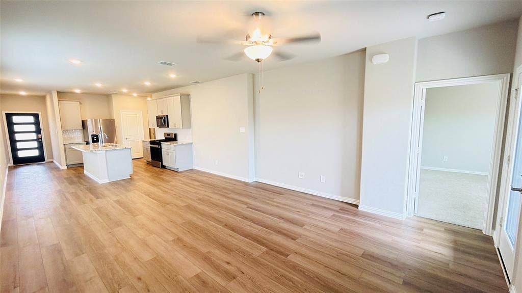 505 Blanton Street, McKinney, TX 75069 Open-concept living area with wood-finish flooring, a kitchen island, stainless steel appliances, recessed lighting, and a ceiling fan