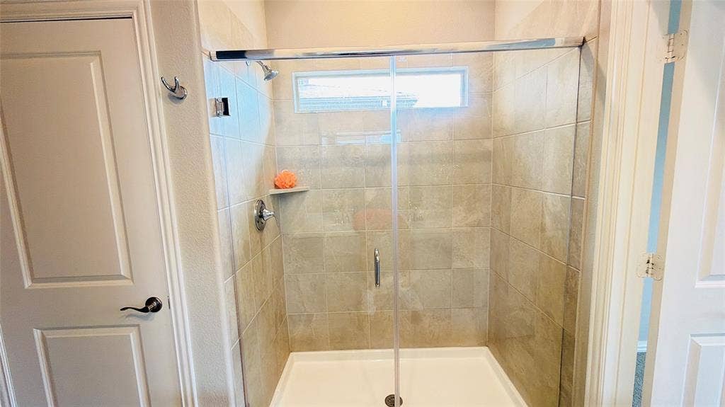 505 Blanton Street, McKinney, TX 75069 Glass-enclosed shower with tile surround, built-in shelf, and transom window