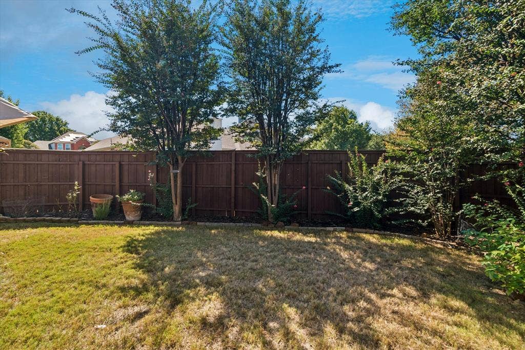 10521 Chablis Lane, Frisco, TX 75035 Fenced backyard featuring mature trees, landscaped beds, and green space
