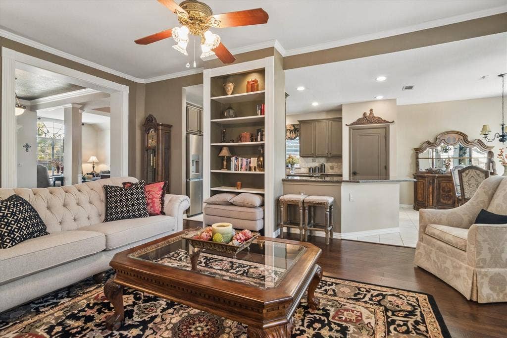 10521 Chablis Lane, Frisco, TX 75035 Hardwood flooring, crown molding, built-in shelving, ceiling fan, and an open pass-through window to the kitchen