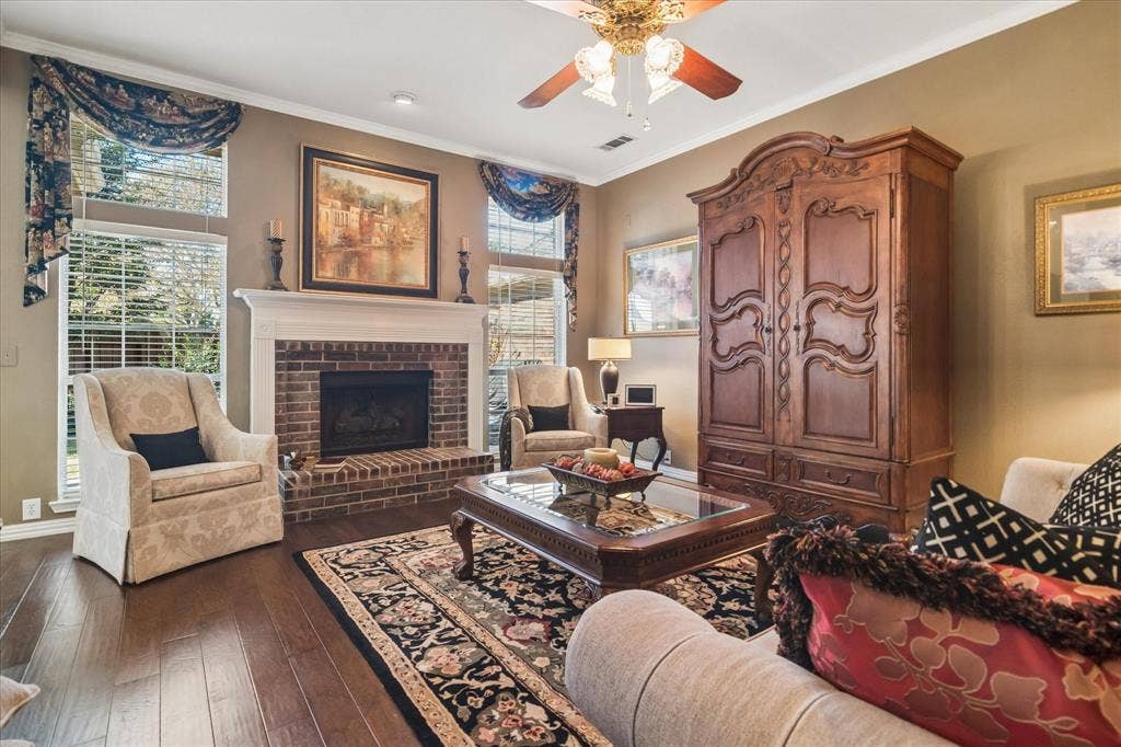 10521 Chablis Lane, Frisco, TX 75035 Warm wood-finish flooring complemented by a brick-surround fireplace with a white mantel