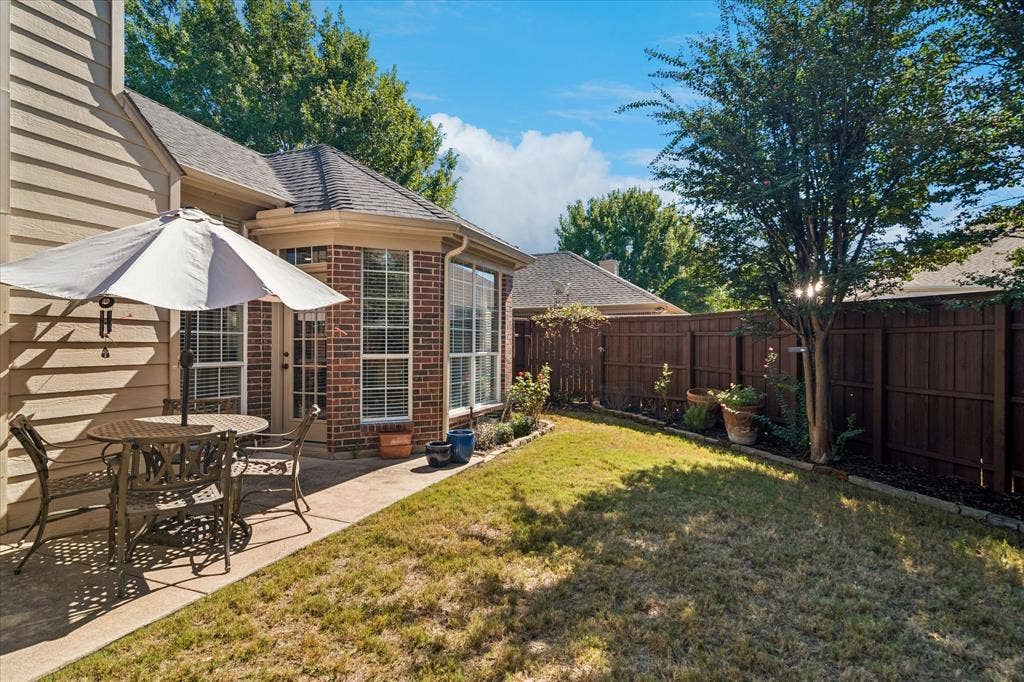 10521 Chablis Lane, Frisco, TX 75035 Private fenced yard featuring a concrete patio and a bay window with brick exterior