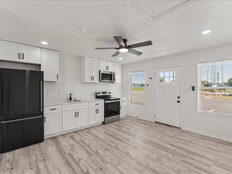 900 S Tool, #12, Tool, TX 75143 Studio Suites include Kitchenette featuring white cabinetry, wood-finish flooring, a stainless steel microwave, and a black refrigerator