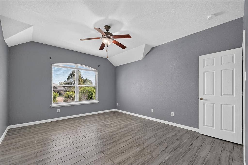 209 Northridge Drive, Wylie, TX 75098 Vaulted ceiling with a ceiling fan, wood-finish flooring, and an arched window