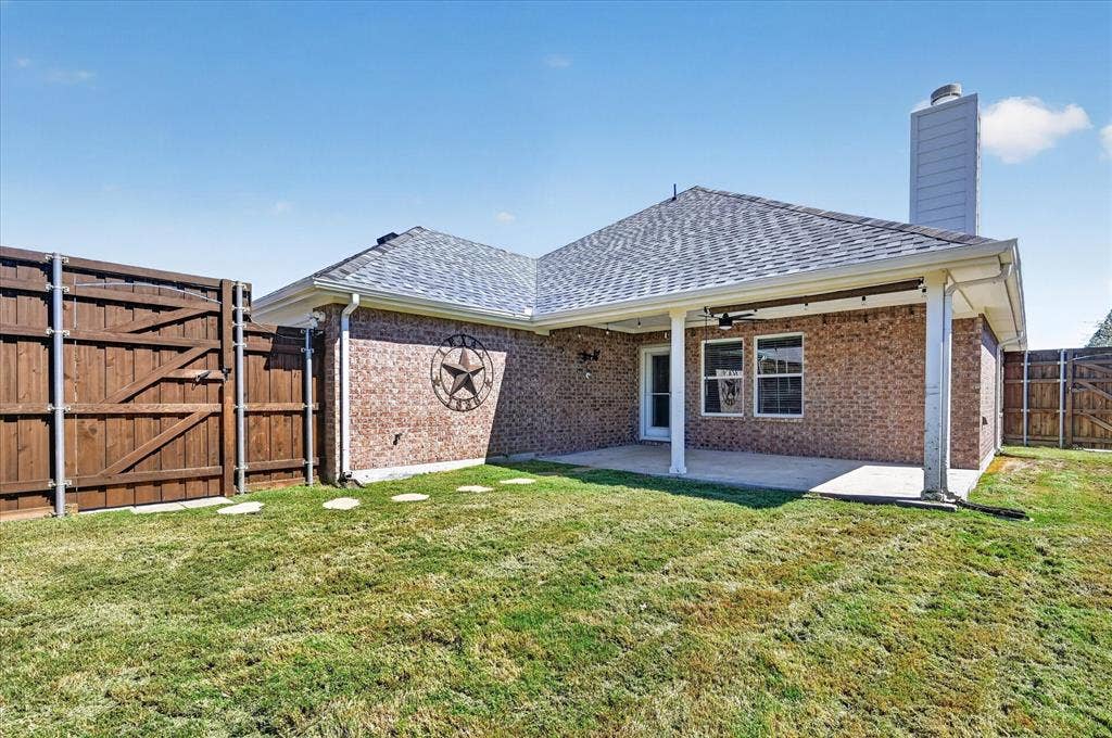 209 Northridge Drive, Wylie, TX 75098 Brick exterior with a covered patio, shingle roof, and a privacy fence