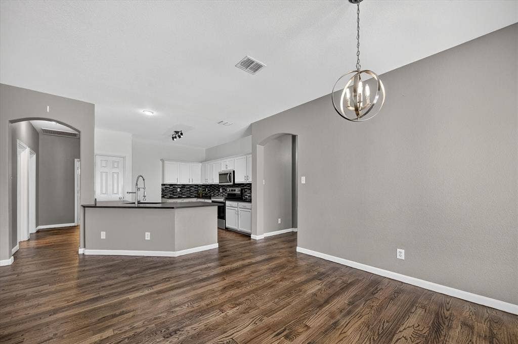 209 Northridge Drive, Wylie, TX 75098 Open-concept living area with dark wood-finish flooring, a contemporary spherical chandelier, and arched doorways