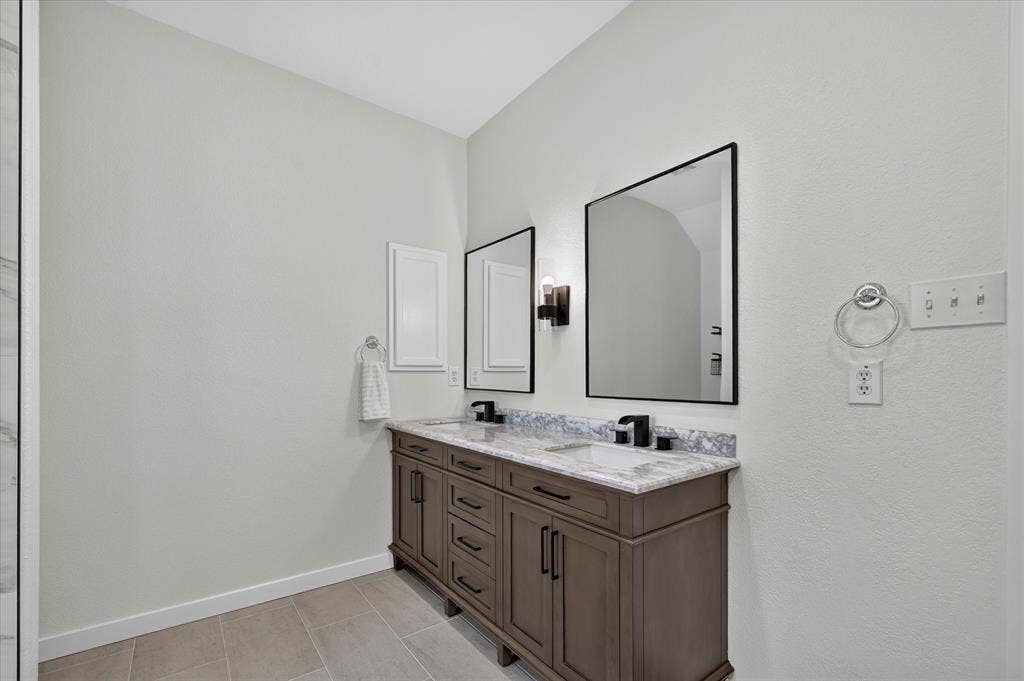 209 Northridge Drive, Wylie, TX 75098 Dual vanity with wood-finish cabinetry, under-mount sinks, and a stone-finish countertop