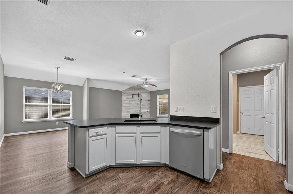 209 Northridge Drive, Wylie, TX 75098 Kitchen island with a dark countertop and white cabinetry, integrated stainless steel dishwasher, wood-finish flooring, and recessed lighting