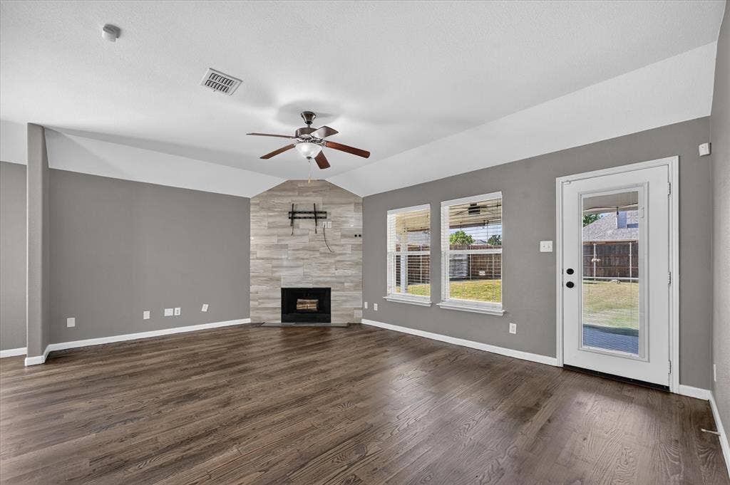 209 Northridge Drive, Wylie, TX 75098 Wood-finish flooring throughout, a vaulted ceiling with a ceiling fan, and a tiled fireplace