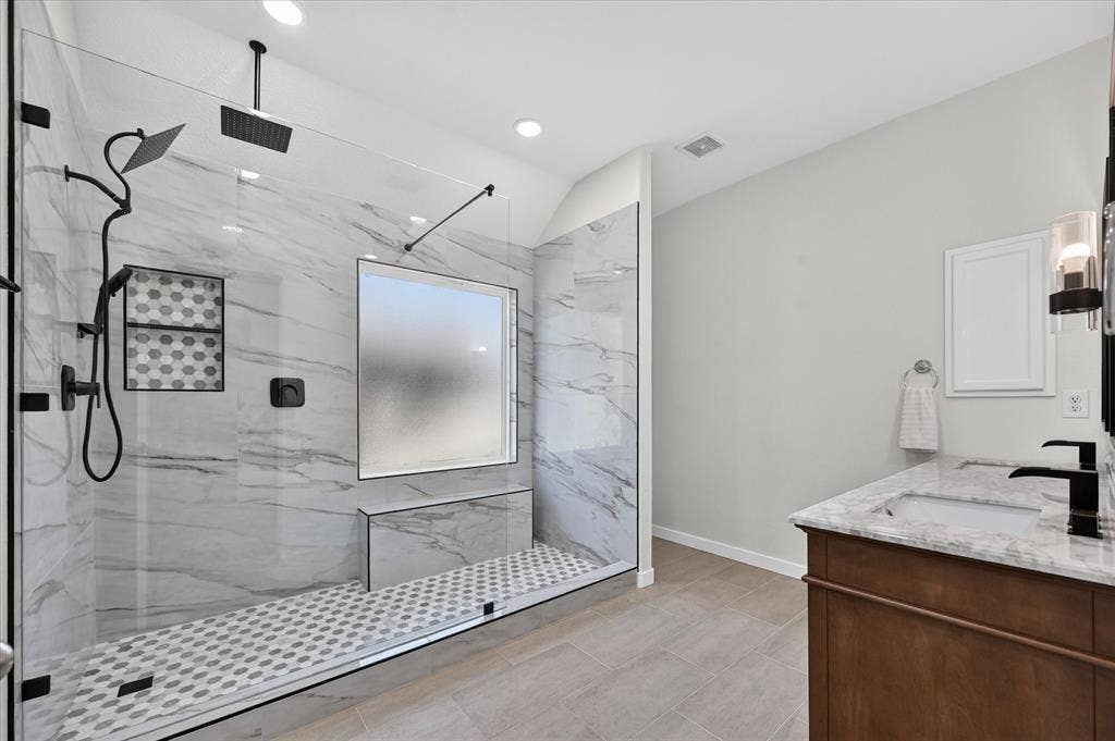 209 Northridge Drive, Wylie, TX 75098 Walk-in shower with clear glass enclosure, marble-look tile walls, dual shower heads, and built-in bench