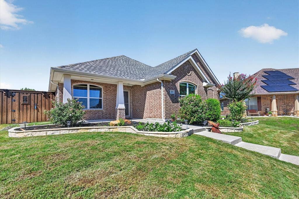 209 Northridge Drive, Wylie, TX 75098 Brick exterior with arched window accents, covered porch with white columns, and a concrete pathway