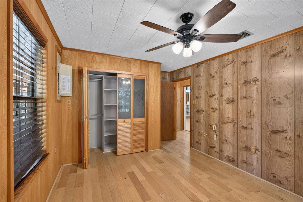 9468 Ranch Lane, Shreveport, LA 71106 Wood-finish flooring, paneled walls, ceiling fan with integrated lighting, and a built-in closet with louvered bi-fold doors