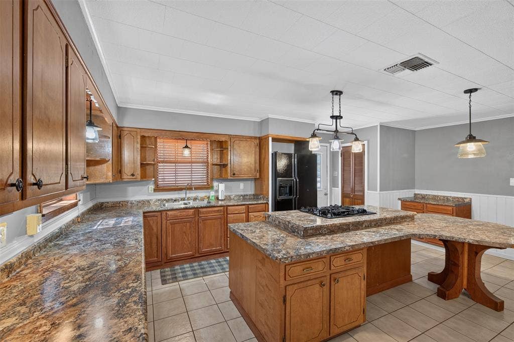 9468 Ranch Lane, Shreveport, LA 71106 Wood-finish cabinetry, patterned countertops, tile flooring, island with stovetop, and pendant lighting fixtures