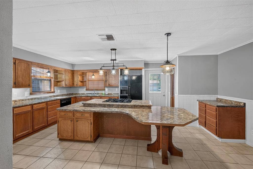 9468 Ranch Lane, Shreveport, LA 71106 Kitchen featuring extensive wood cabinetry, L-shaped island with integrated seating, tiled flooring, and pendant lighting fixtures