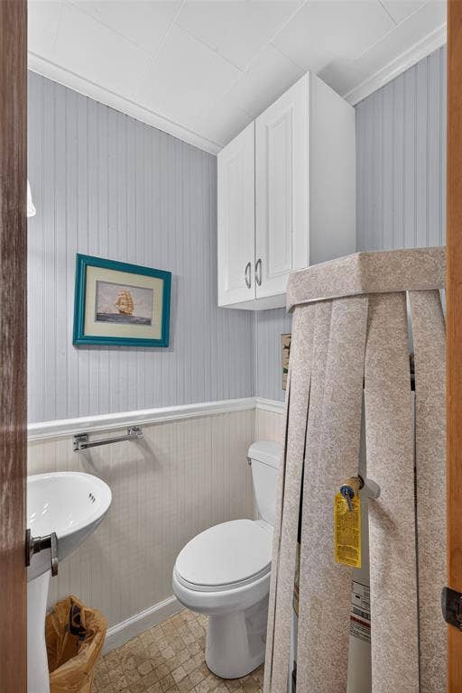 9468 Ranch Lane, Shreveport, LA 71106 Pedestal sink with chrome faucet, toilet, wall-mounted cabinetry, and beadboard paneling