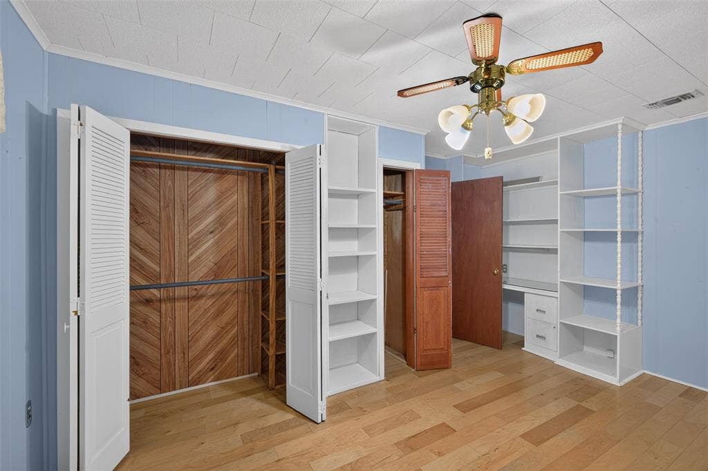 9468 Ranch Lane, Shreveport, LA 71106 Wood-finish flooring, built-in shelving, ceiling fan, bi-fold louvered closet doors, and wood-paneled closet interior
