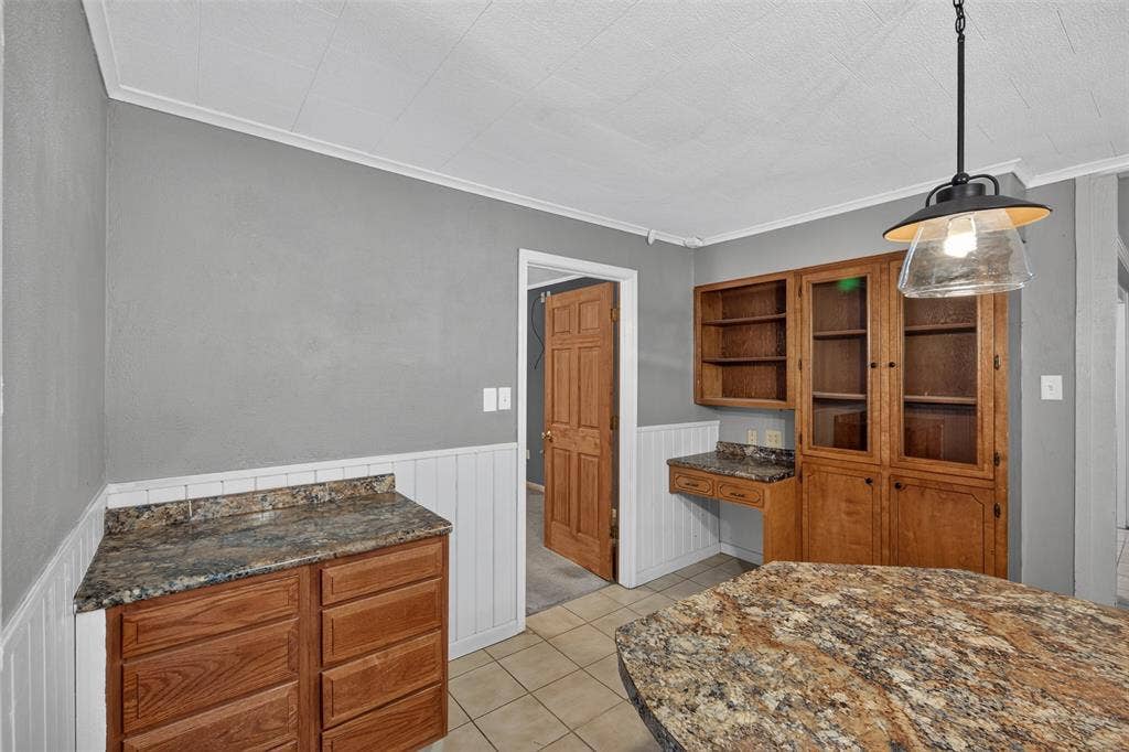 9468 Ranch Lane, Shreveport, LA 71106 Built-in cabinetry with glass-front uppers, patterned countertops, and a pendant light fixture