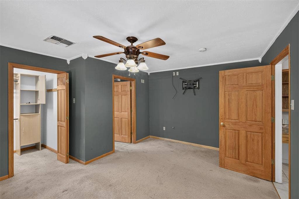 9468 Ranch Lane, Shreveport, LA 71106 Carpeted room featuring a ceiling fan with integrated lighting, wood-finish interior doors, and built-in closet shelving