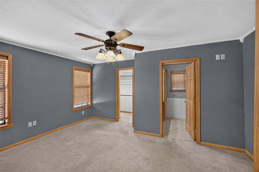 9468 Ranch Lane, Shreveport, LA 71106 Carpeted room featuring a ceiling fan with integrated lighting, wood-trimmed windows with blinds, and wood-paneled doors