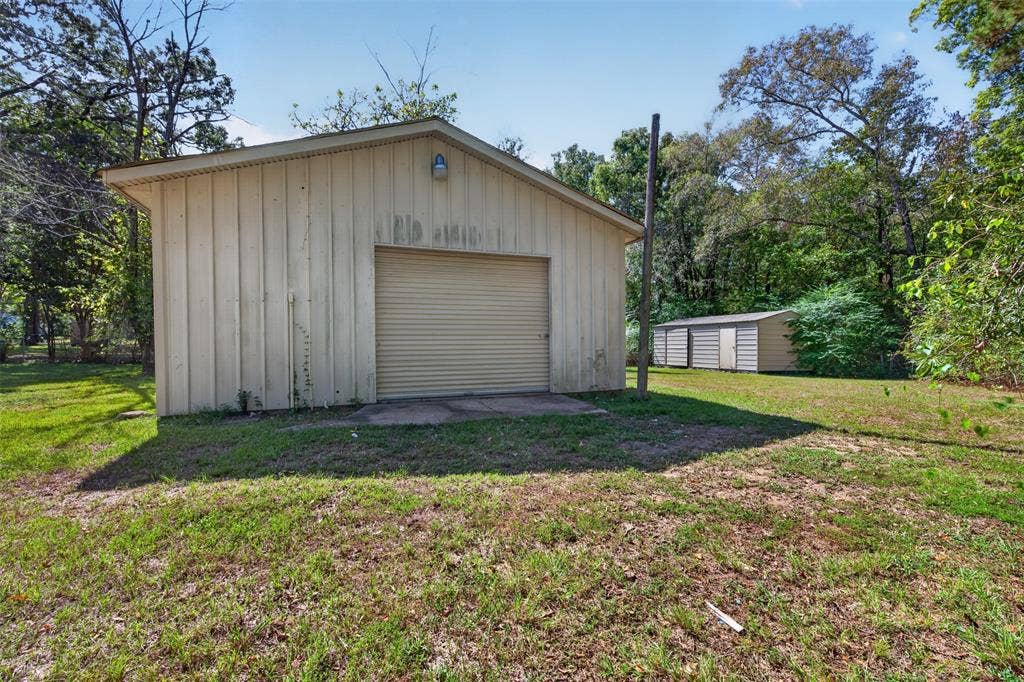 9468 Ranch Lane, Shreveport, LA 71106 Detached auxiliary building with a roll-up door, accompanied by a secondary storage structure on a grass lawn