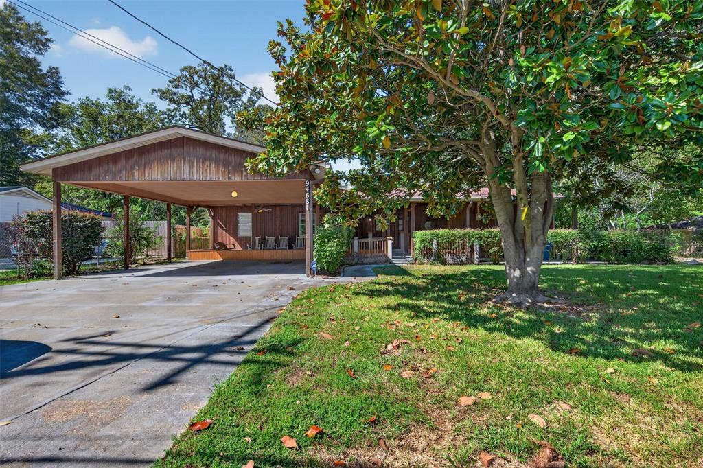 9468 Ranch Lane, Shreveport, LA 71106 Covered carport, concrete driveway, mature tree, established lawn, and exterior wood-finish siding