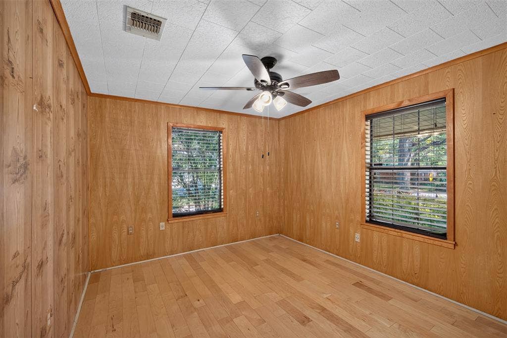 9468 Ranch Lane, Shreveport, LA 71106 Wood-finish wall paneling, light wood-finish flooring, and a ceiling fan with integrated lighting
