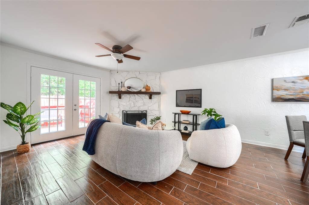 1600 Brentwood Drive, Irving, TX 75061 Wood-finish flooring throughout, white textured walls, corner fireplace with a wood mantle, and a ceiling fan