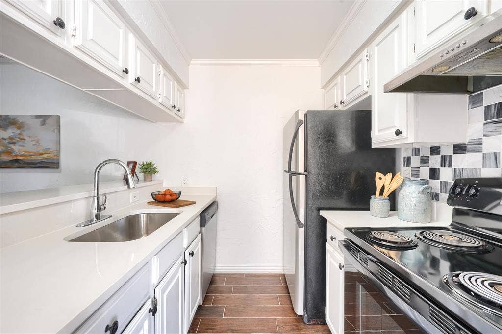 1600 Brentwood Drive, Irving, TX 75061 Galley kitchen featuring white cabinetry, light-toned countertops, a stainless steel sink, and wood-finish flooring