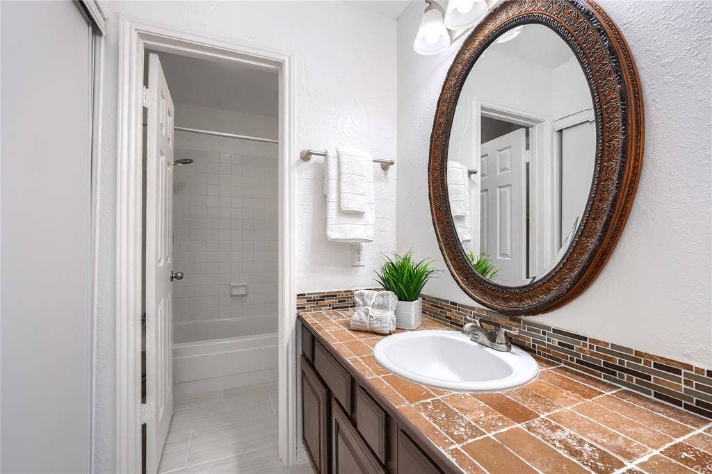 1600 Brentwood Drive, Irving, TX 75061 Bathroom with an ornate framed mirror, dark wood vanity cabinetry, and a textured countertop