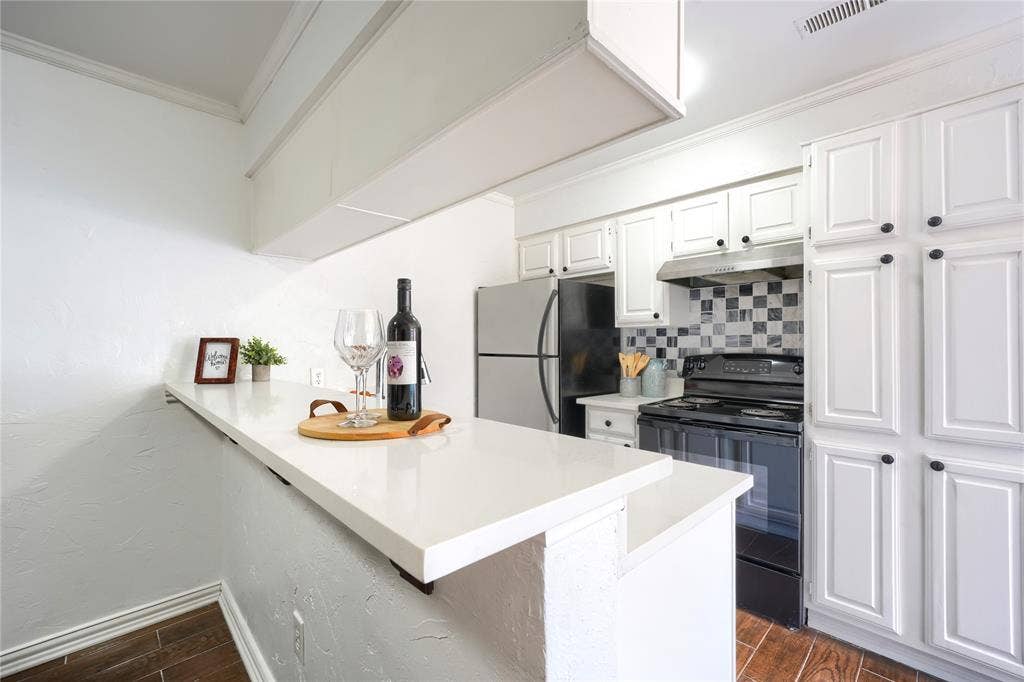 1600 Brentwood Drive, Irving, TX 75061 Kitchen featuring white cabinetry, light countertops, checkerboard tile backsplash, and wood-finish flooring