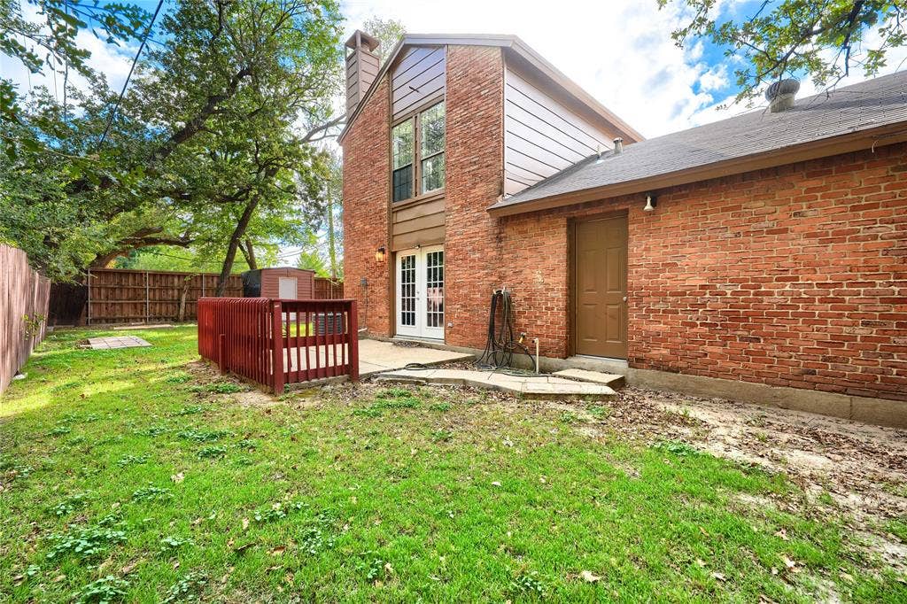 1600 Brentwood Drive, Irving, TX 75061 Brick exterior with white double doors, featuring a backyard area with a wooden fence and mature trees