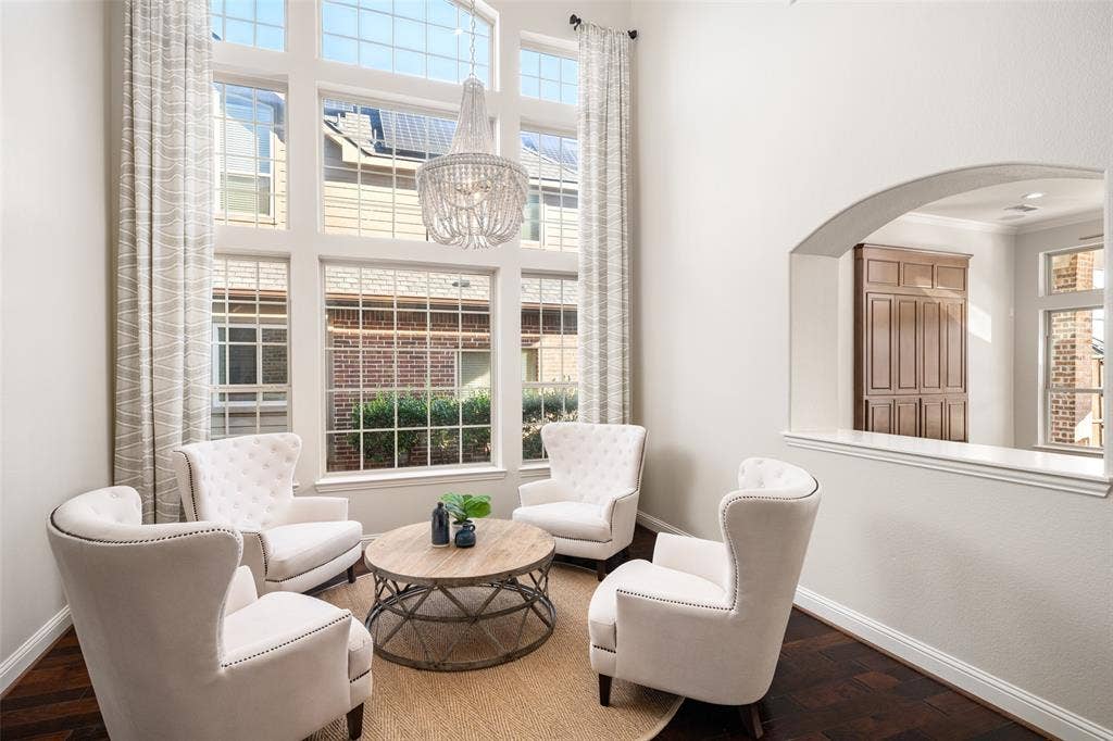Two-story window wall, wood-finish flooring, vaulted ceiling, arched pass-through, and a decorative chandelier