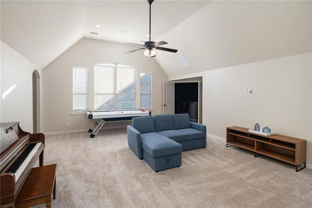 Vaulted ceiling with an integrated ceiling fan and recessed lighting, light-toned carpeting, arched doorway, and bay window with blinds