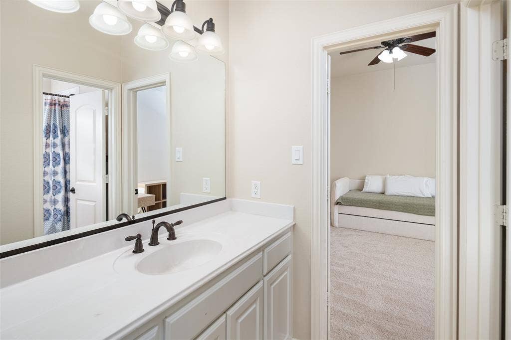 White vanity with a single basin sink, bronze-finish faucet, and an overhead multi-light fixture