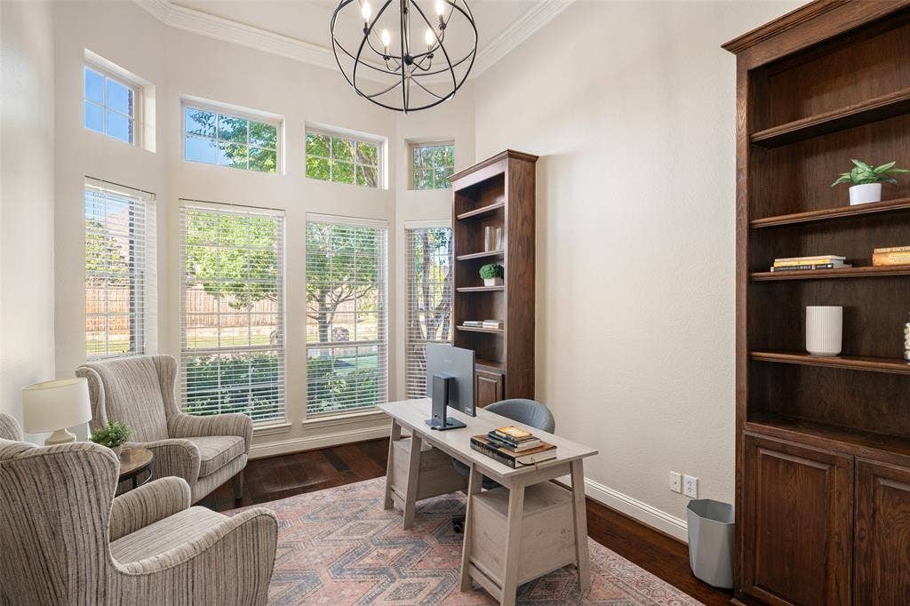 Two-story space featuring a floor-to-ceiling window arrangement, rich wood-finish flooring, a contemporary chandelier, and built-in wood shelving