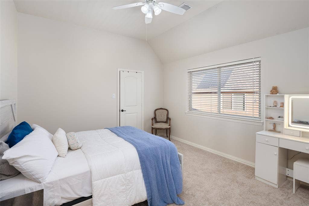 Vaulted ceiling, ceiling fan, white paneled door, window with horizontal blinds, and neutral carpet flooring