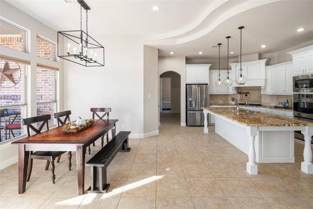 Expansive kitchen featuring a large island with stone countertop, white cabinetry, and stainless steel appliances