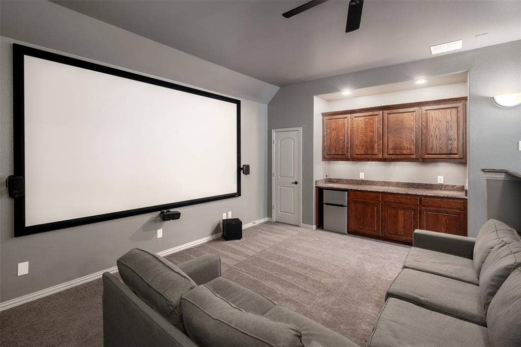 Integrated projection screen, built-in cabinetry with stone-finish countertop, recessed lighting, ceiling fan, and carpeted flooring
