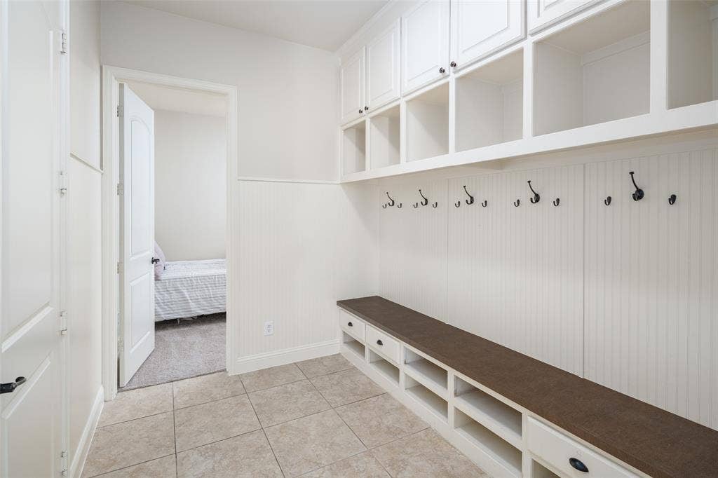 Built-in storage solutions with upper cabinetry, open shelving, and a bench with shoe cubbies