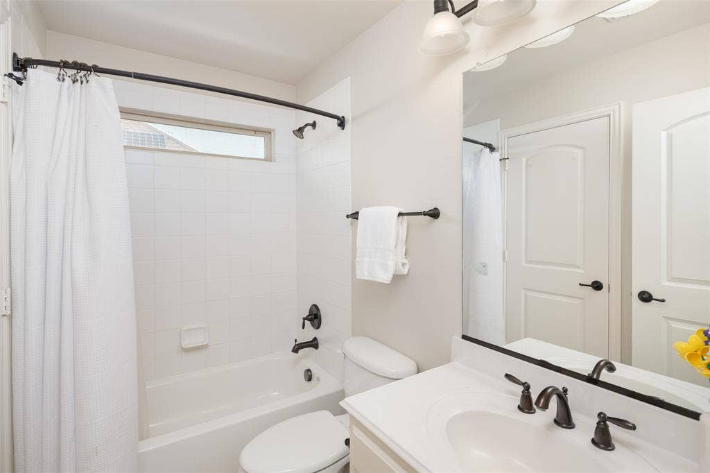 Bathroom featuring a built-in bathtub with white tile surround, a single vanity with an integrated sink, and an overhead lighting fixture