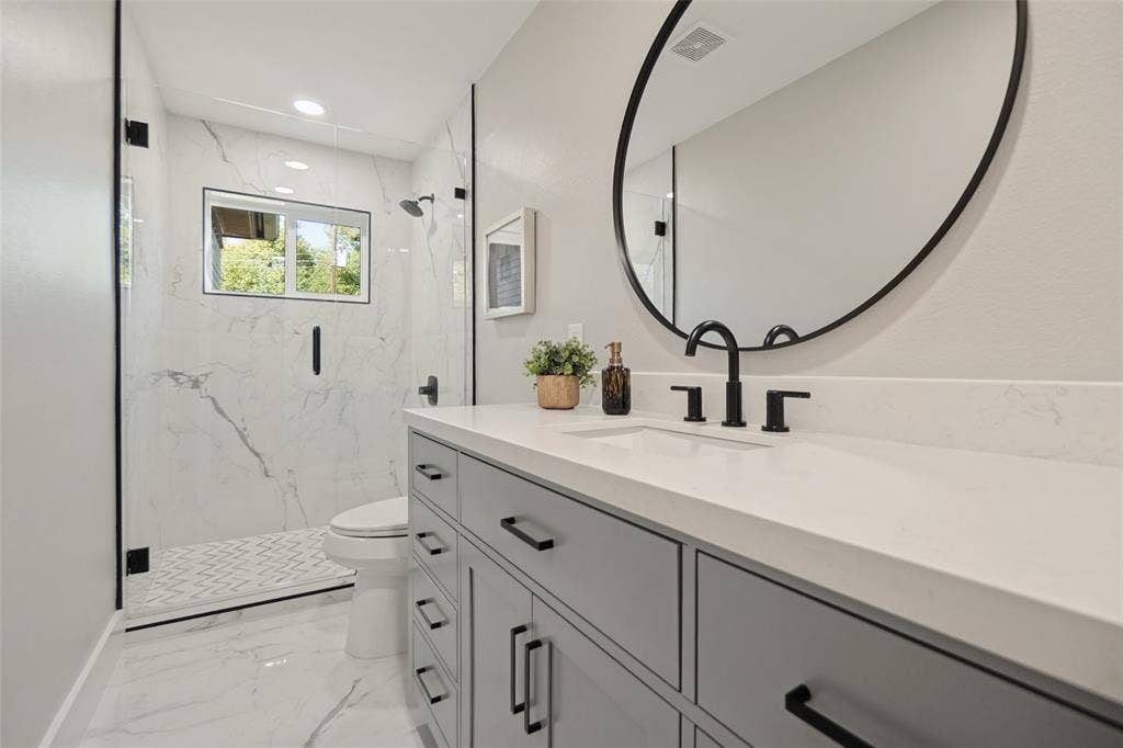 3129 Flowerdale Lane, Dallas, TX 75229 Vanity with solid surface countertop, matte black fixtures, and an oval mirror