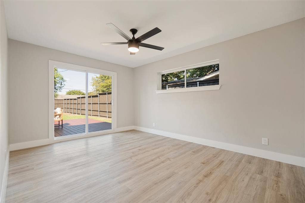 3129 Flowerdale Lane, Dallas, TX 75229 Wood-finish flooring, sliding glass doors to exterior decking, window, ceiling fan with integrated lighting, and neutral wall tones