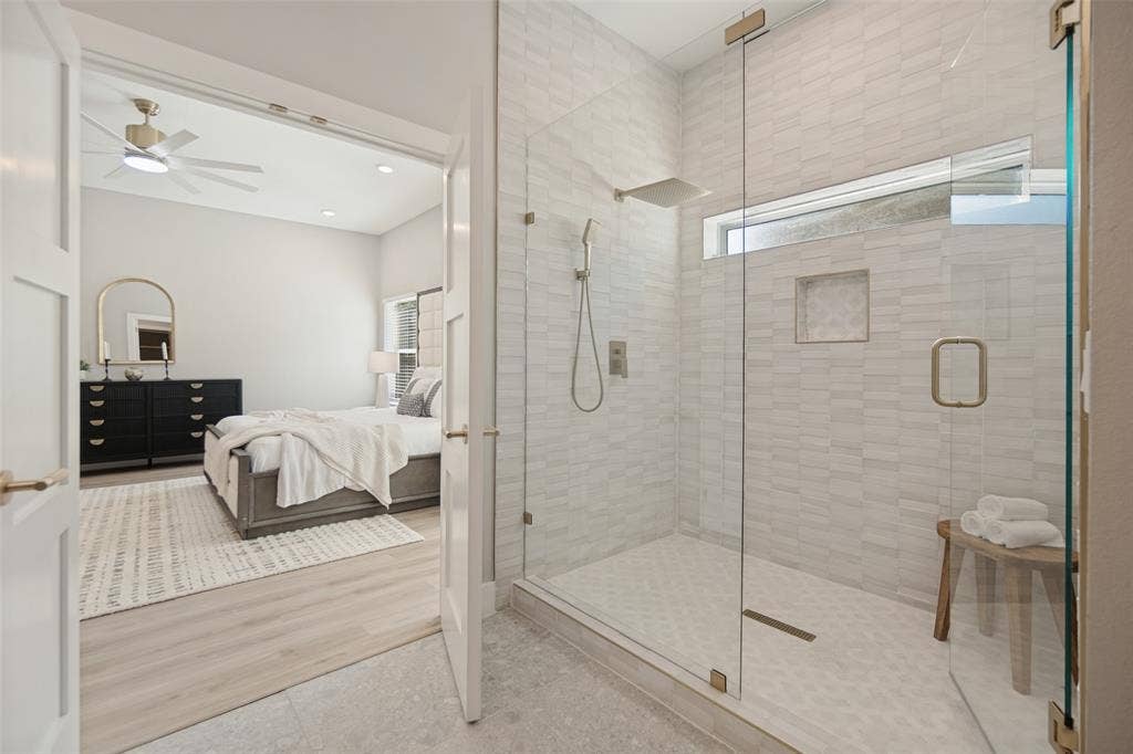 3129 Flowerdale Lane, Dallas, TX 75229 Frameless glass shower enclosure with a rain shower head, hand-held shower, and built-in niche