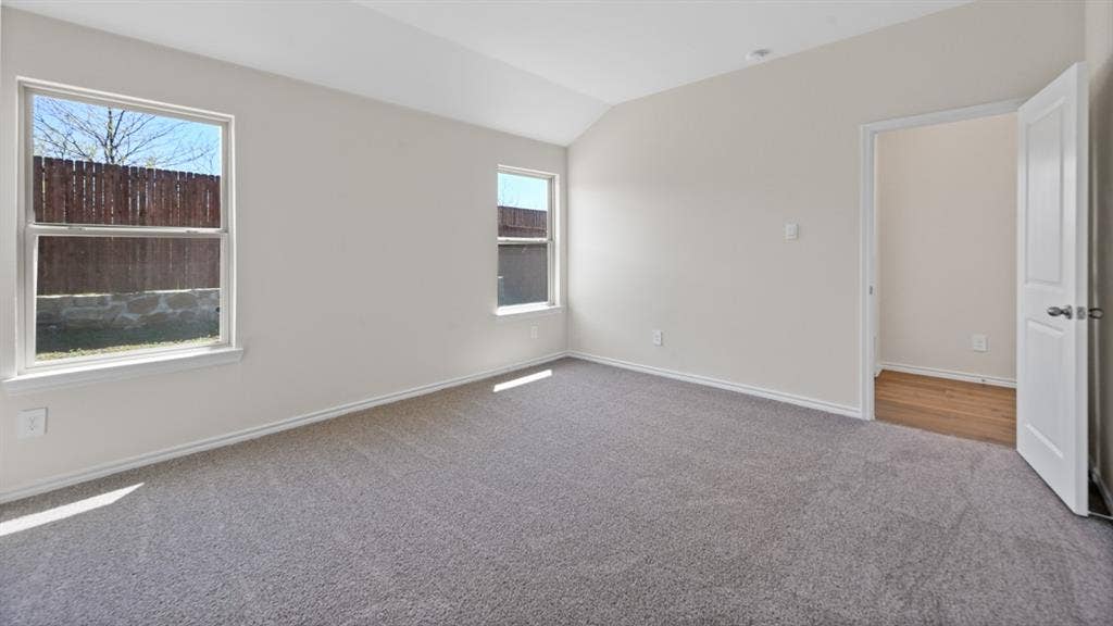 5431 Cormorant Grove, Crandall, TX 75114 Spacious room featuring vaulted ceilings, light gray wall paint, and gray carpet flooring