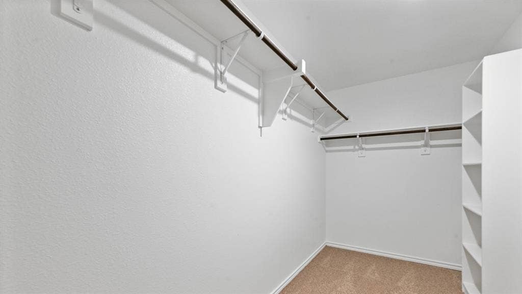 5431 Cormorant Grove, Crandall, TX 75114 Walk-in closet featuring built-in shelving, dual hanging rods, and neutral carpet flooring
