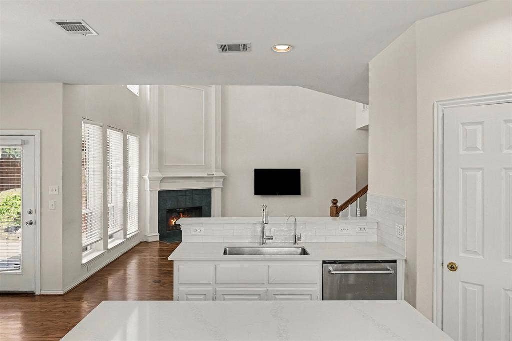7813 San Isabel Drive, Plano, TX 75025 Stainless steel sink, white subway tile backsplash, white cabinetry, integrated dishwasher, and wood-finish flooring