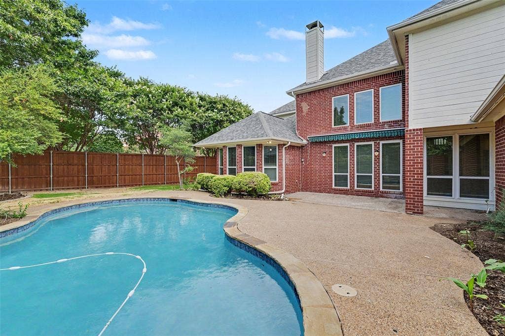 7813 San Isabel Drive, Plano, TX 75025 Expansive outdoor area featuring a swimming pool, concrete patio, and a brick exterior with multiple windows