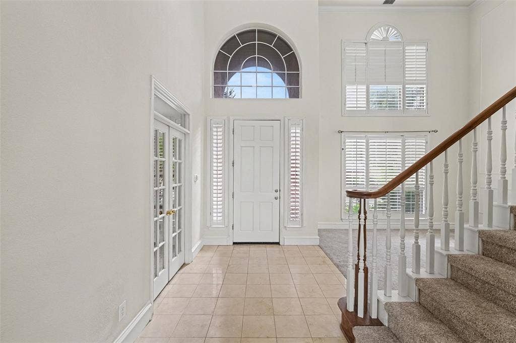 7813 San Isabel Drive, Plano, TX 75025 Two-story foyer with high ceilings, arched transom window, ceramic tile flooring, and French doors